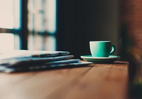 Coffee cup and newspapers on table